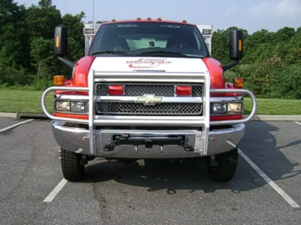 Exterior view of small fire truck showing cab, body compartments, and wheel/tire area.