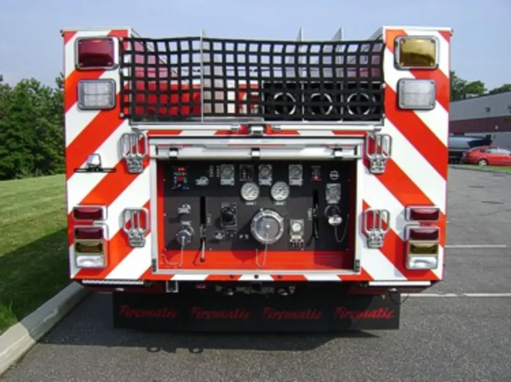 Exterior view of small fire truck showing cab, body compartments, and wheel/tire area.