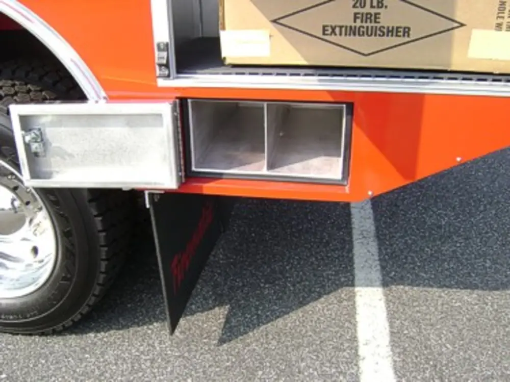 Exterior view of small fire truck showing cab, body compartments, and wheel/tire area.