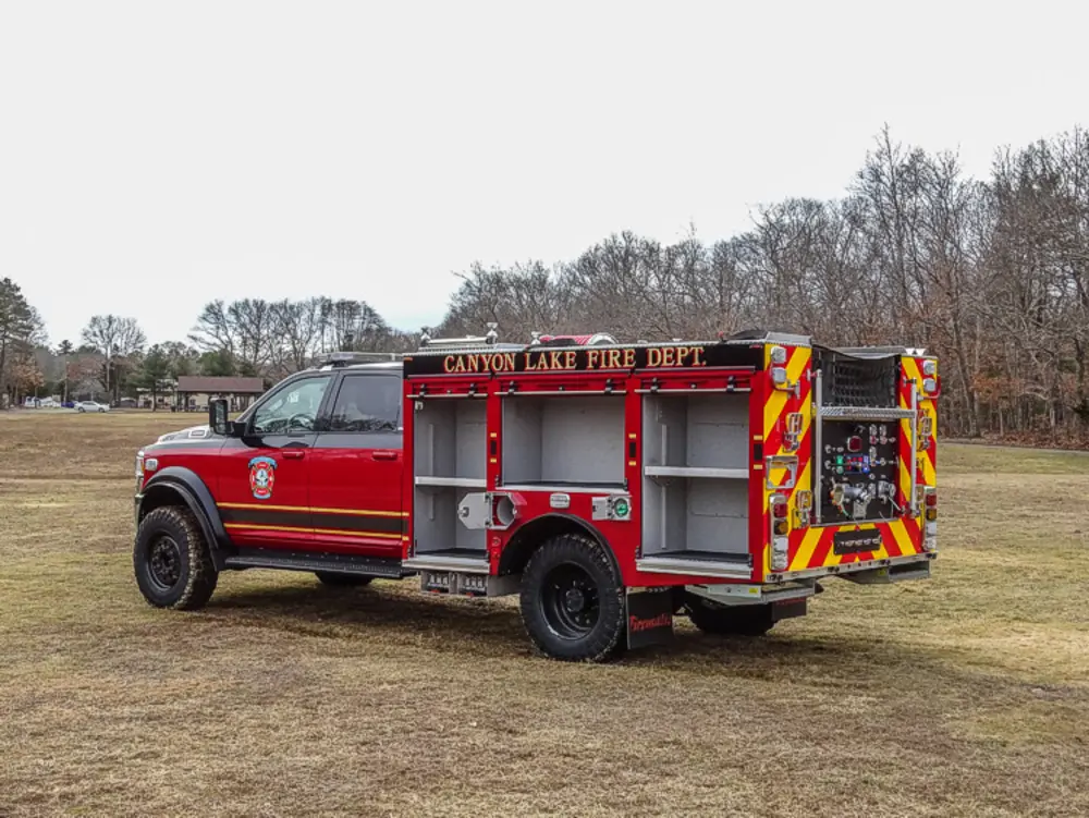 Exterior view of small fire truck showing cab, body compartments, and wheel/tire area.