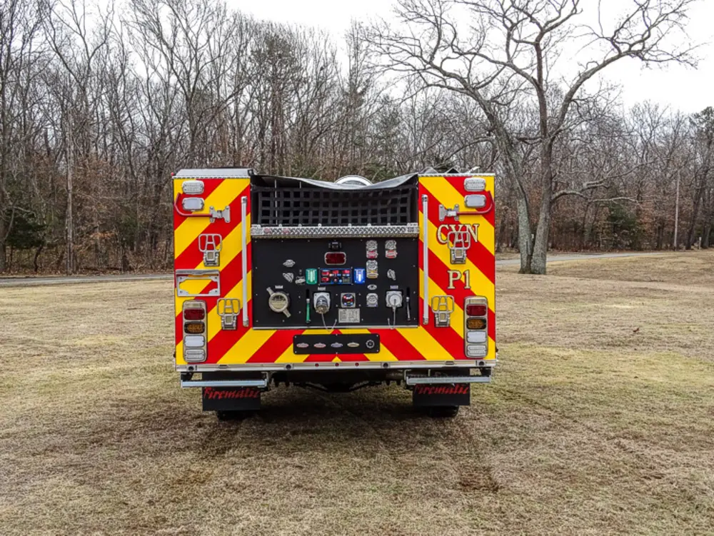 Exterior view of small fire truck showing cab, body compartments, and wheel/tire area.