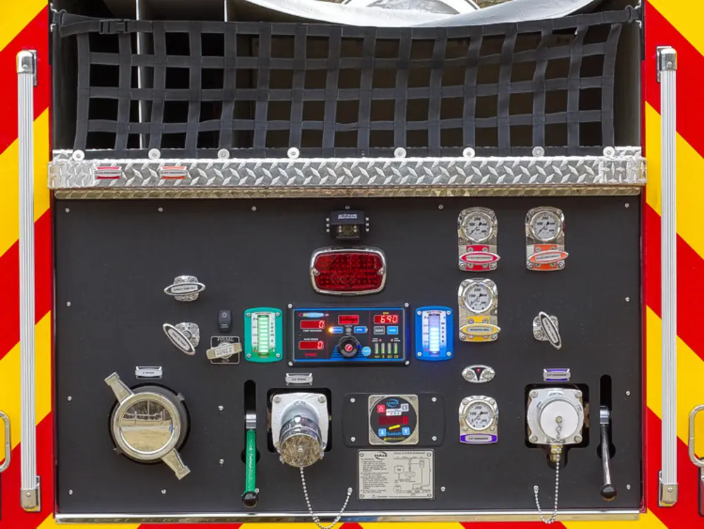 Exterior view of small fire truck showing cab, body compartments, and wheel/tire area.