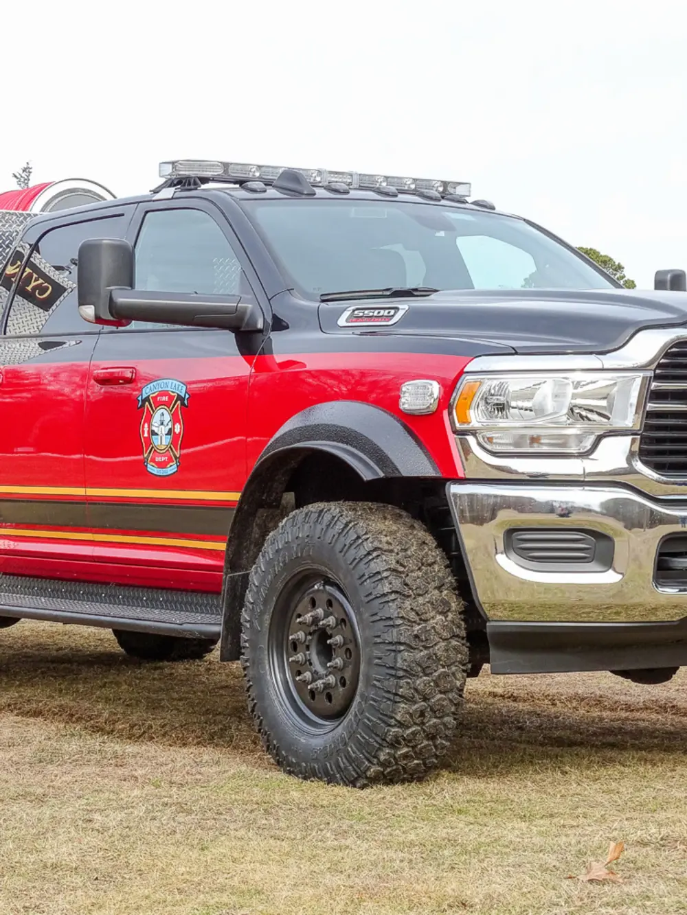 Exterior view of small fire truck showing cab, body compartments, and wheel/tire area.