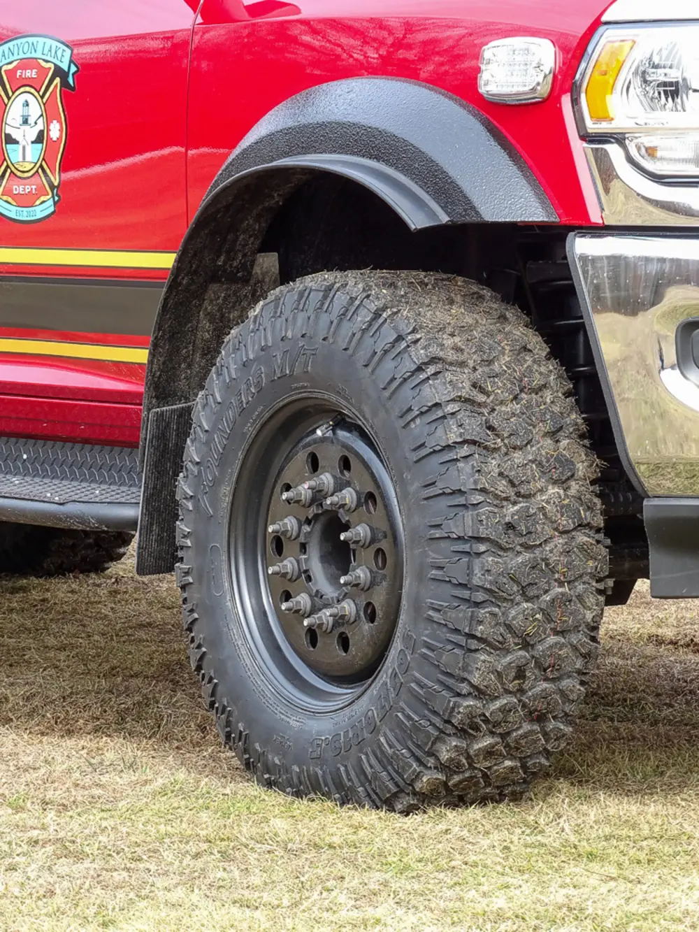Exterior view of small fire truck showing cab, body compartments, and wheel/tire area.
