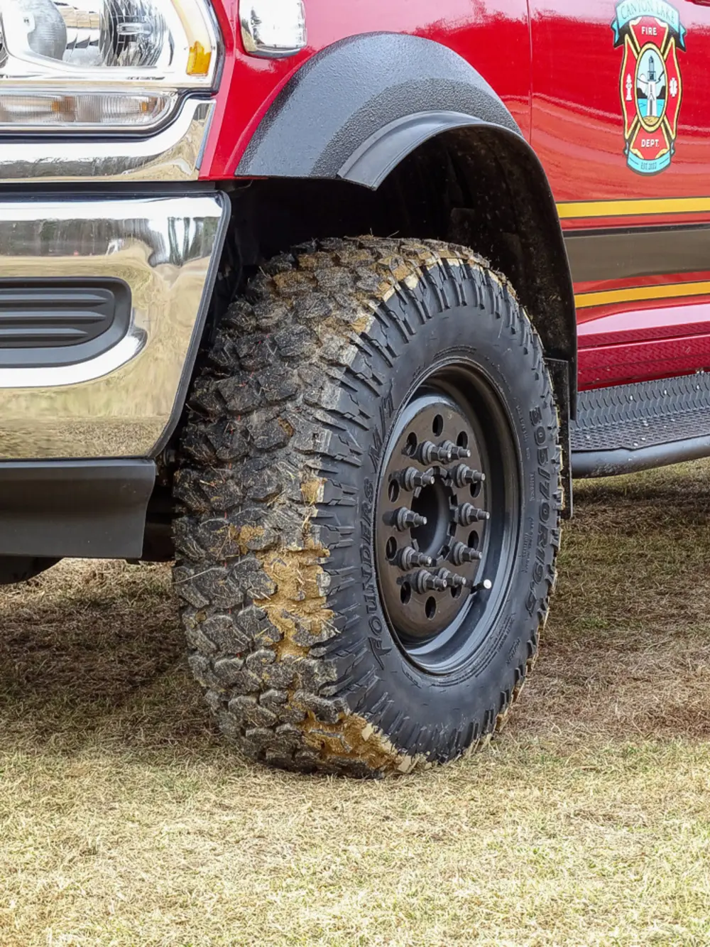 Exterior view of small fire truck showing cab, body compartments, and wheel/tire area.