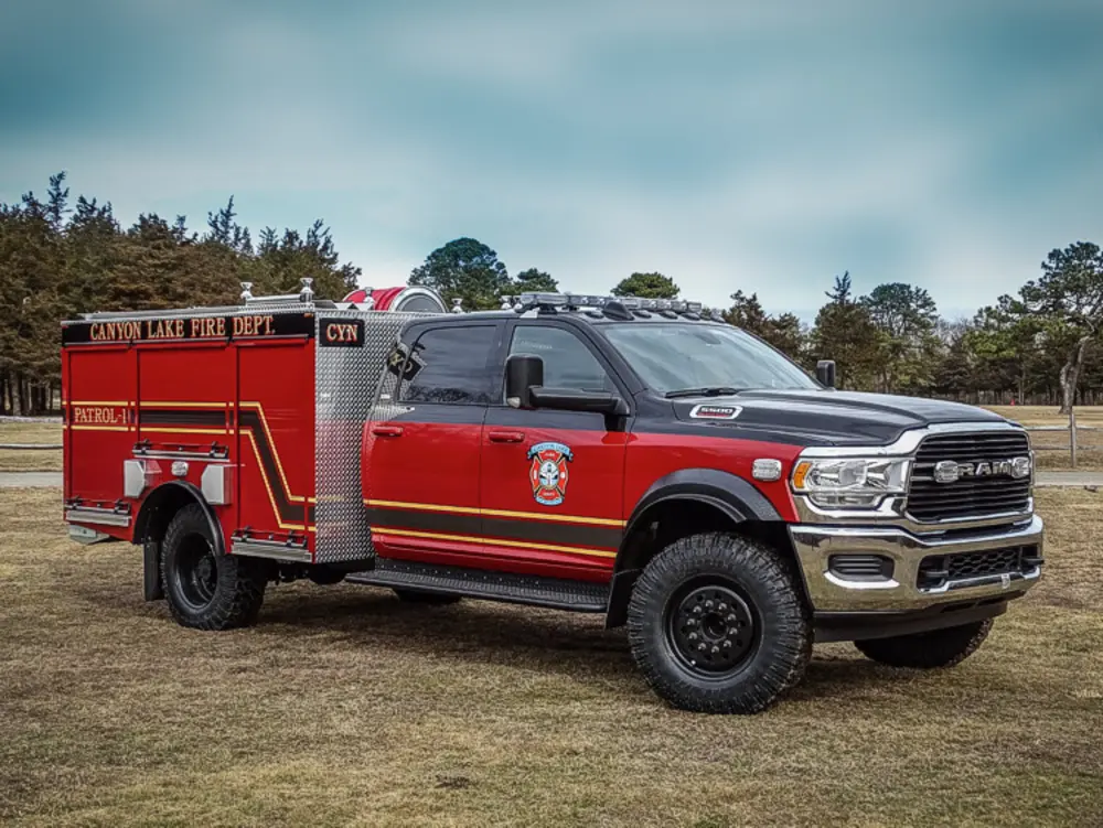 Exterior view of small fire truck showing cab, body compartments, and wheel/tire area.