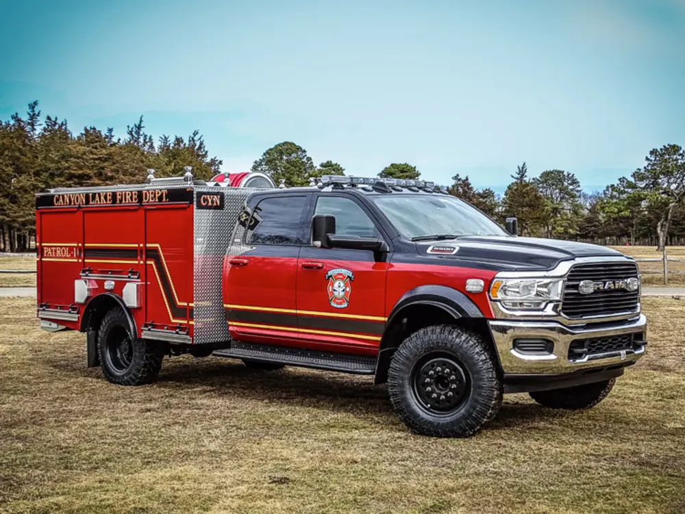 Exterior view of small fire truck showing cab, body compartments, and wheel/tire area.
