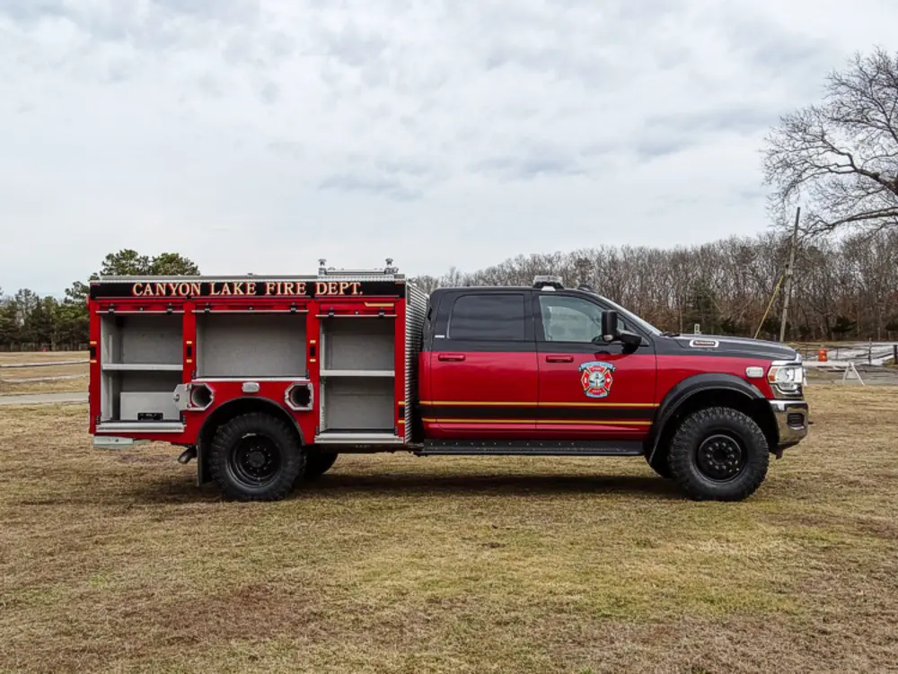 Exterior view of small fire truck showing cab, body compartments, and wheel/tire area.