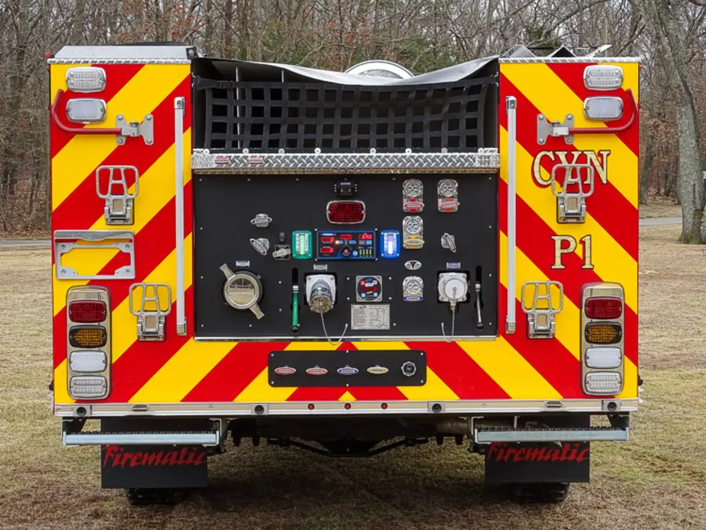 Exterior view of small fire truck showing cab, body compartments, and wheel/tire area.