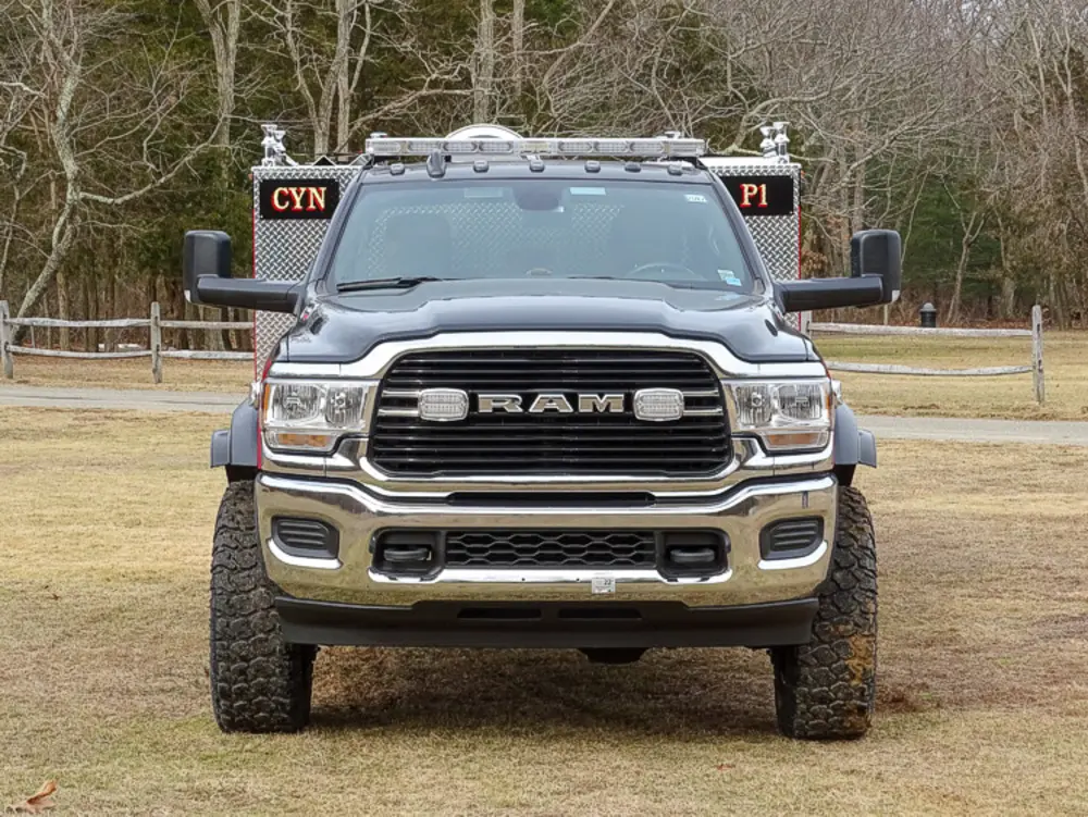 Exterior view of small fire truck showing cab, body compartments, and wheel/tire area.