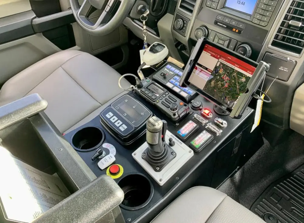 Exterior view of small fire truck showing cab, body compartments, and wheel/tire area.