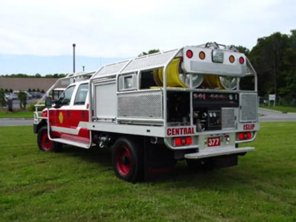 Exterior view of small fire truck showing cab, body compartments, and wheel/tire area.