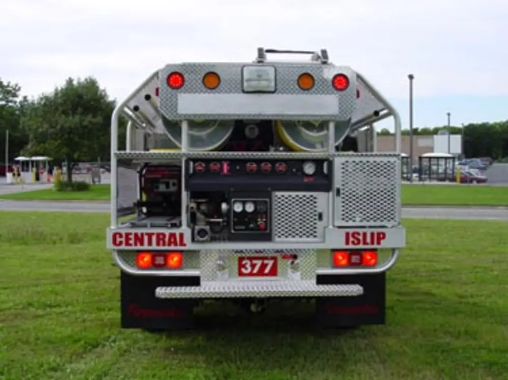 Exterior view of small fire truck showing cab, body compartments, and wheel/tire area.
