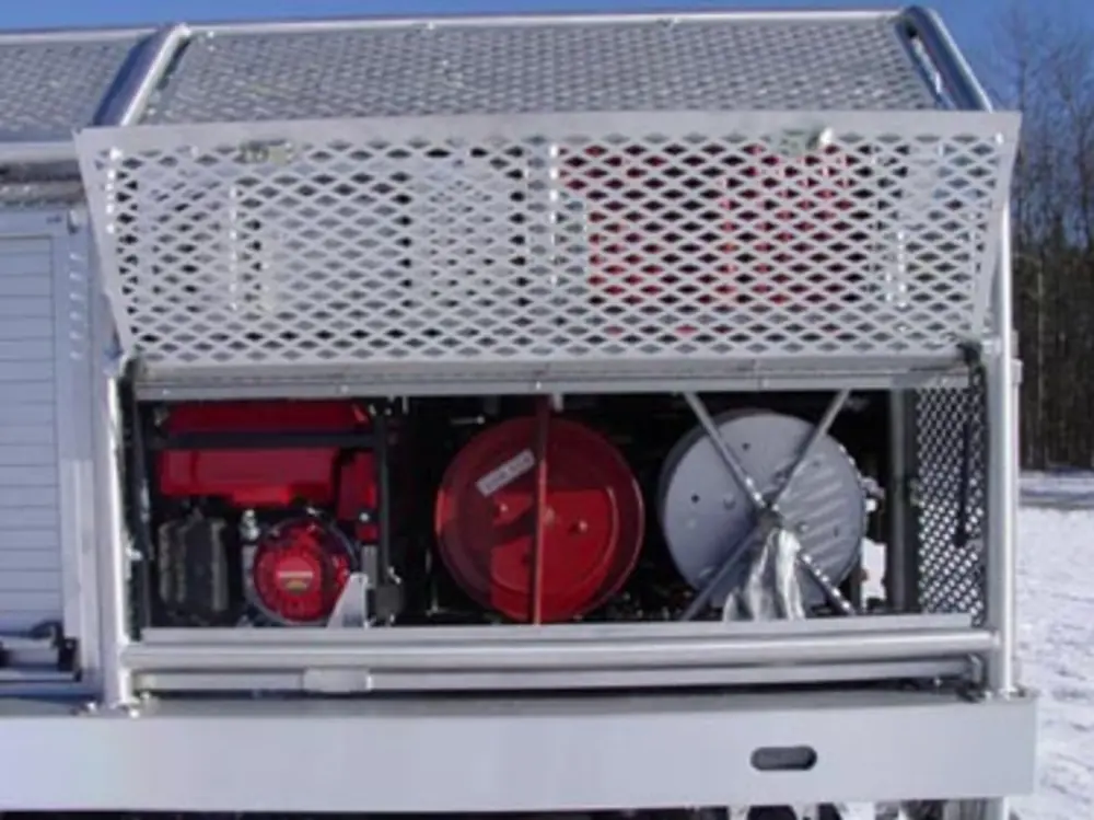 Exterior view of small fire truck showing cab, body compartments, and wheel/tire area.