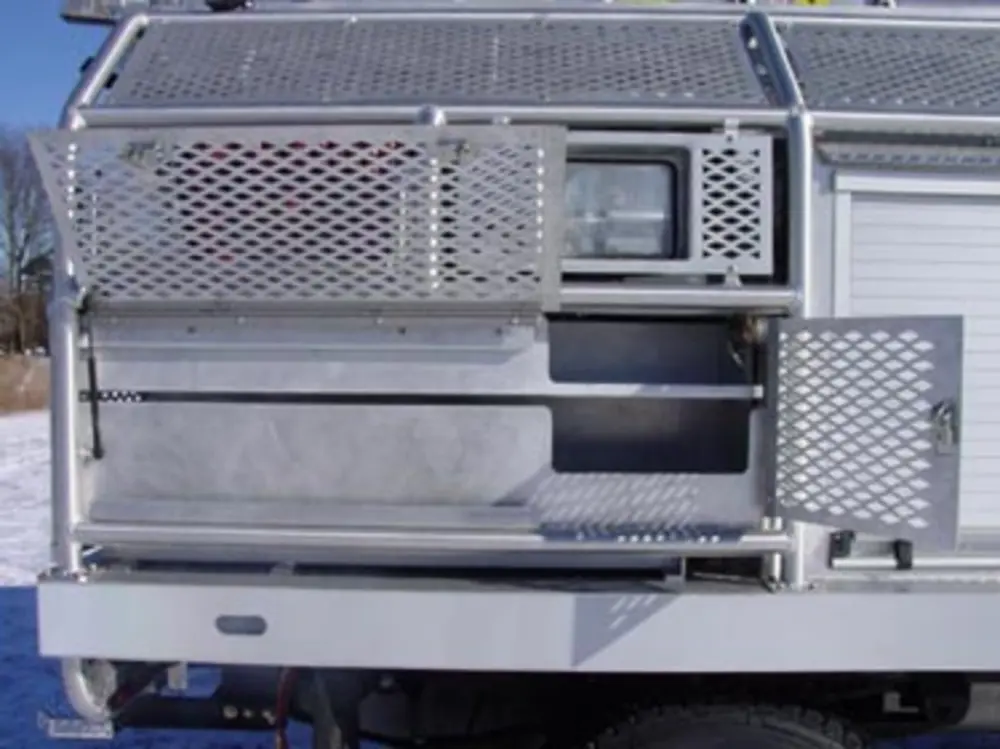 Exterior view of small fire truck showing cab, body compartments, and wheel/tire area.