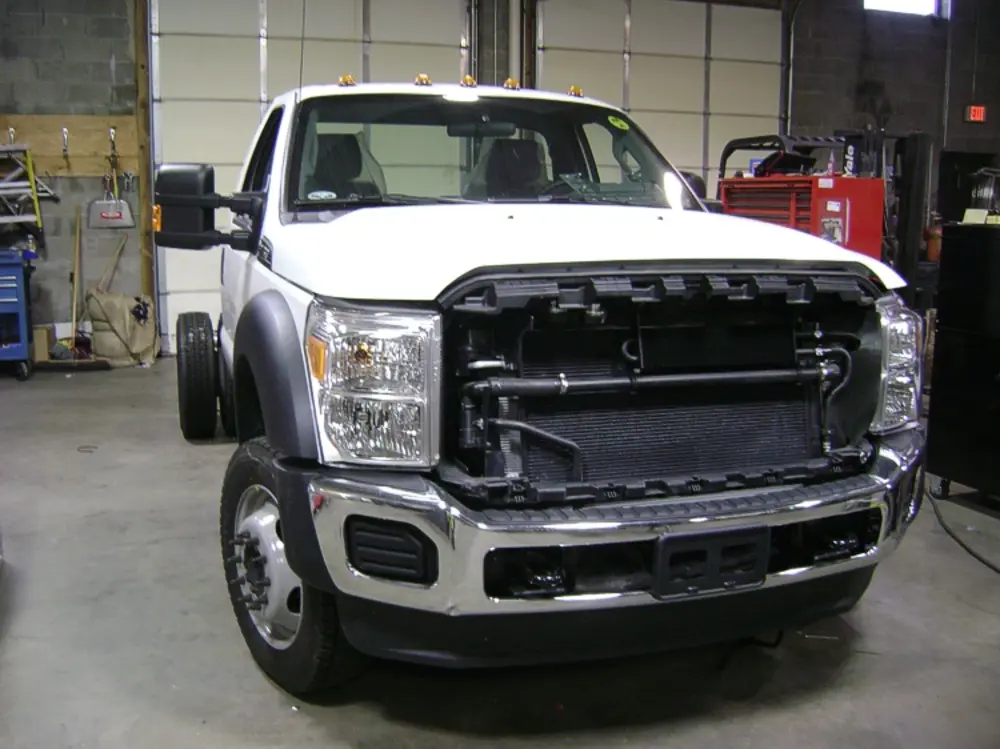 Exterior view of small fire truck showing cab, body compartments, and wheel/tire area.