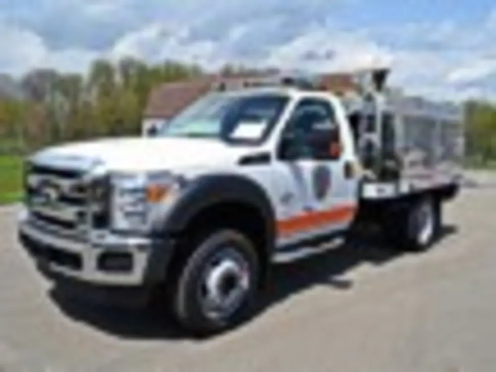 Exterior view of small fire truck showing cab, body compartments, and wheel/tire area.