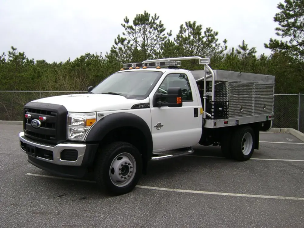 Exterior view of small fire truck showing cab, body compartments, and wheel/tire area.