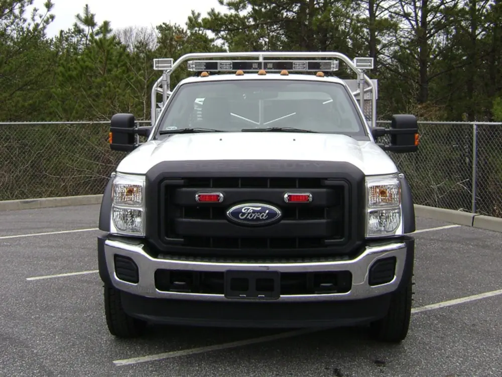 Exterior view of small fire truck showing cab, body compartments, and wheel/tire area.
