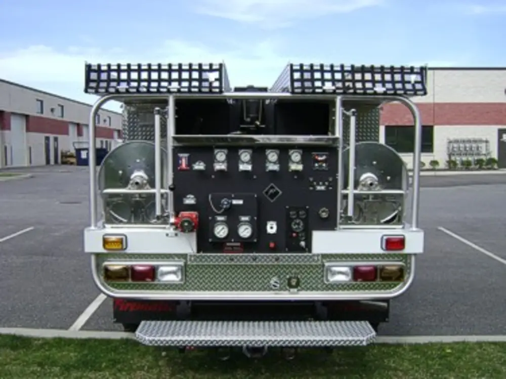 Exterior view of small fire truck showing cab, body compartments, and wheel/tire area.
