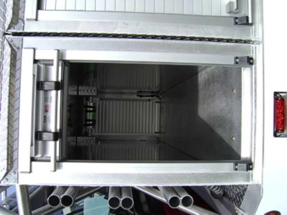 Exterior view of small fire truck showing cab, body compartments, and wheel/tire area.