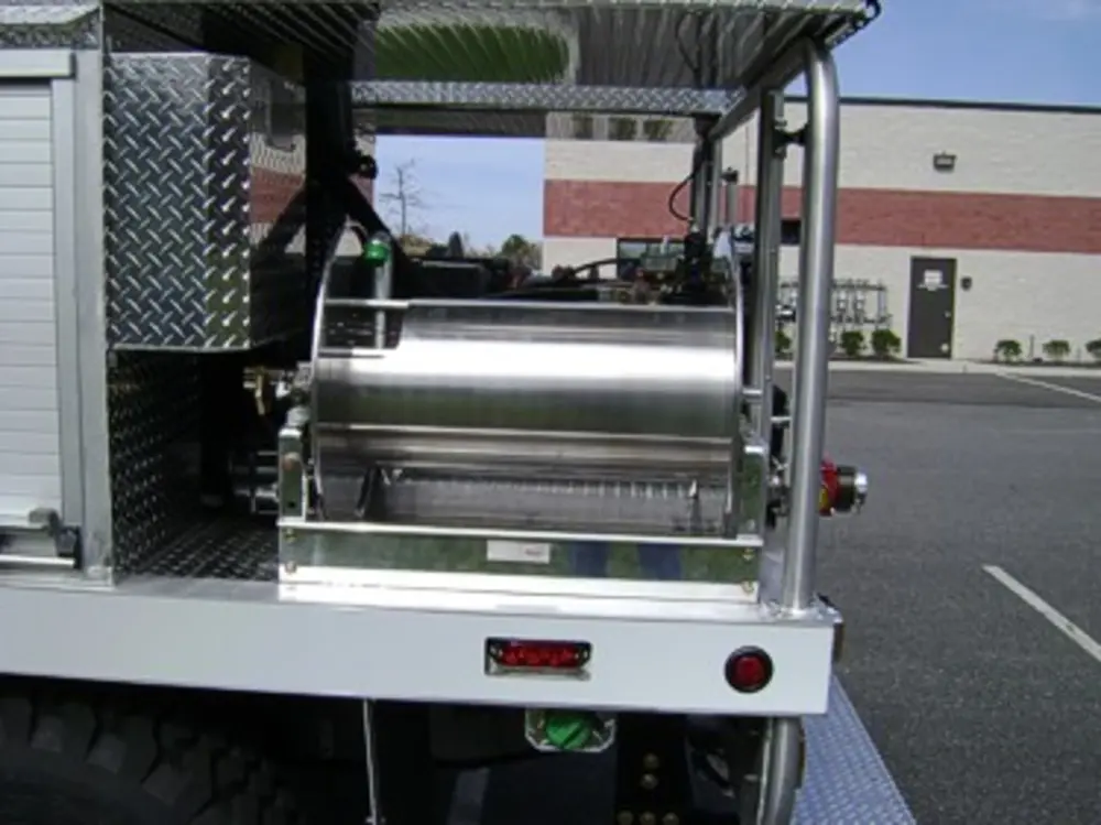 Exterior view of small fire truck showing cab, body compartments, and wheel/tire area.