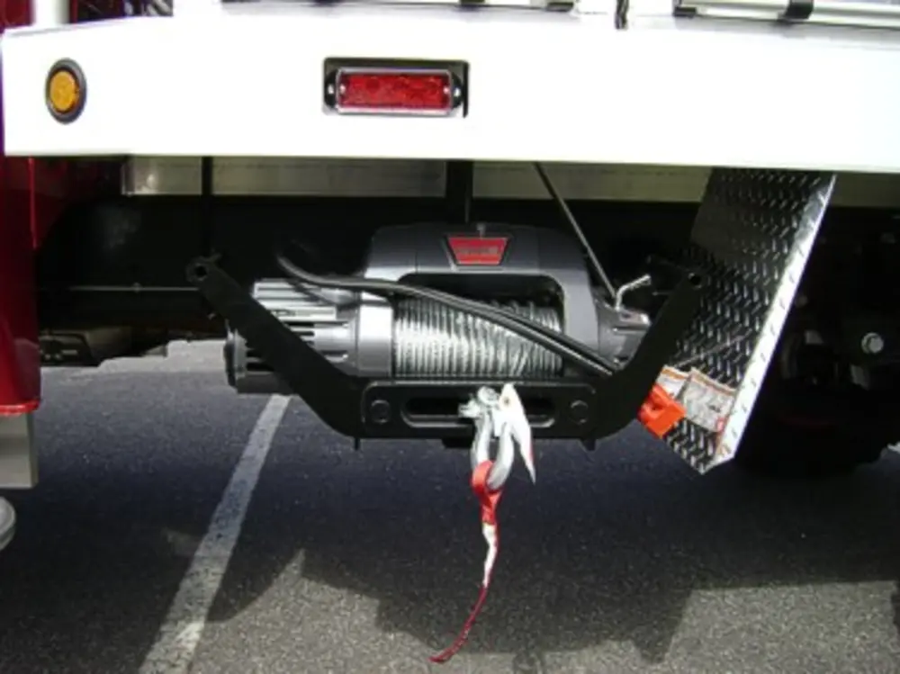 Exterior view of small fire truck showing cab, body compartments, and wheel/tire area.