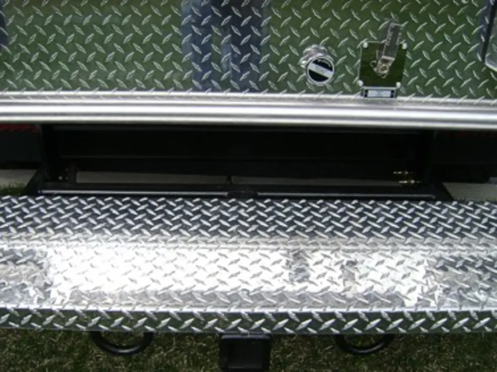 Exterior view of small fire truck showing cab, body compartments, and wheel/tire area.