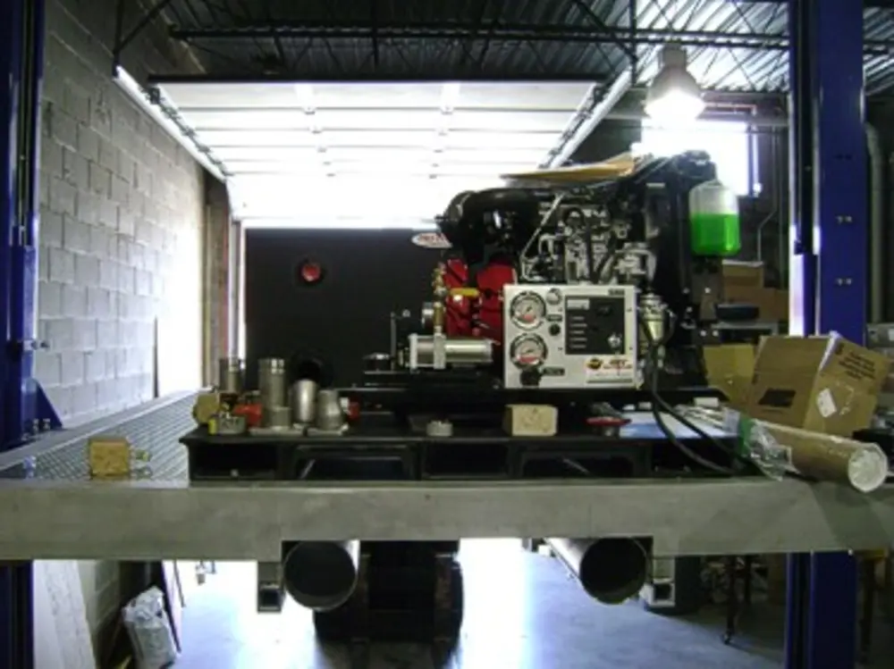 Exterior view of small fire truck showing cab, body compartments, and wheel/tire area.