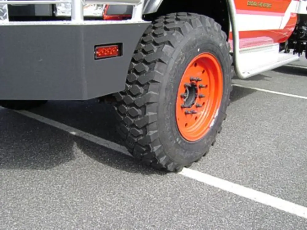 Exterior view of small fire truck showing cab, body compartments, and wheel/tire area.