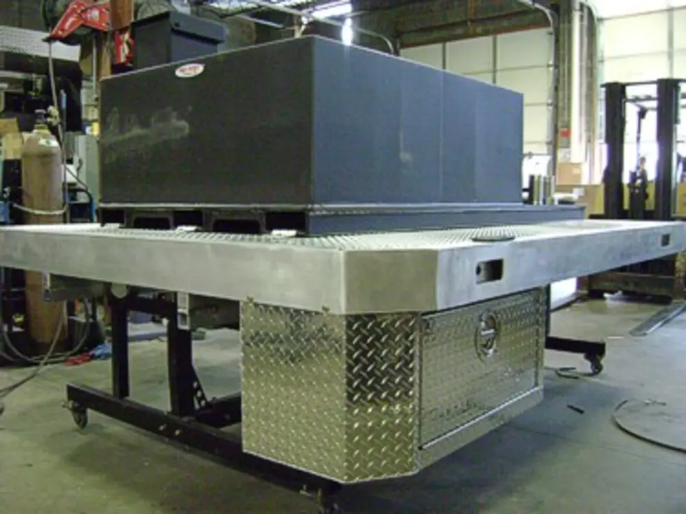 Exterior view of small fire truck showing cab, body compartments, and wheel/tire area.