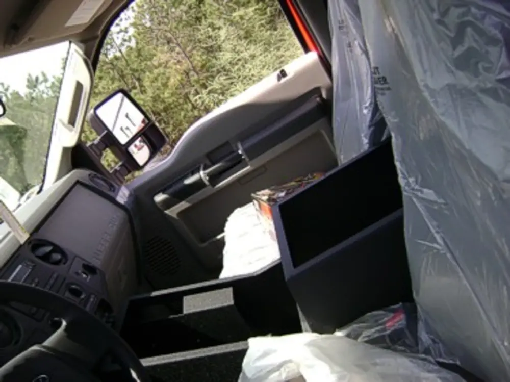 Exterior view of small fire truck showing cab, body compartments, and wheel/tire area.