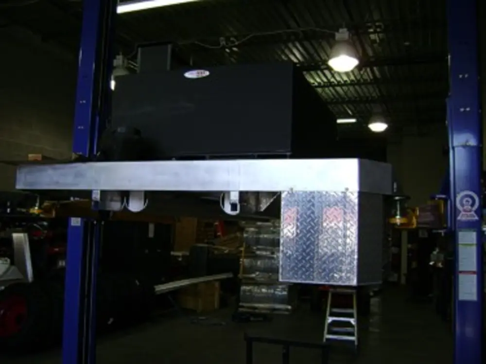 Exterior view of small fire truck showing cab, body compartments, and wheel/tire area.