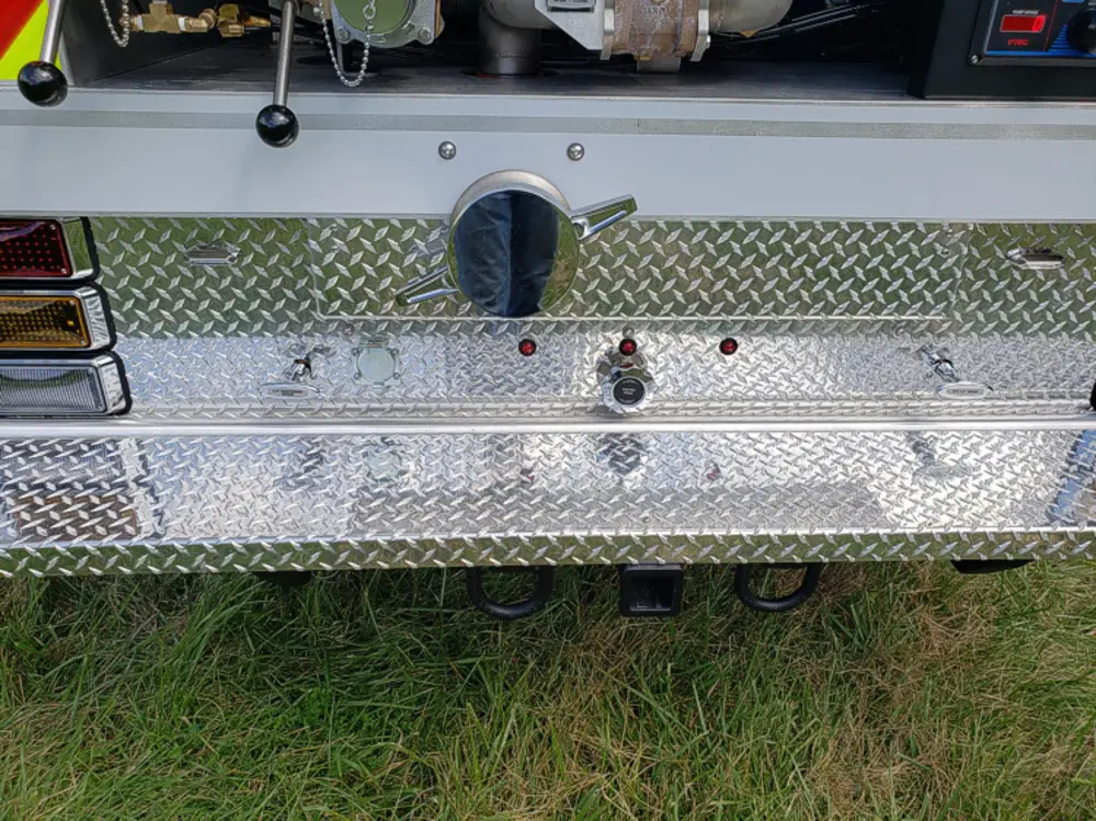 Exterior view of small fire truck showing cab, body compartments, and wheel/tire area.