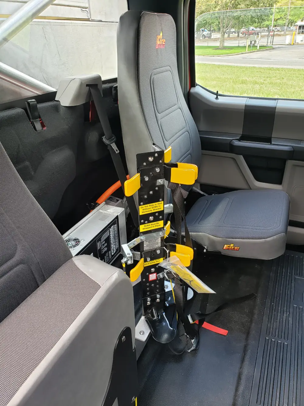 Exterior view of small fire truck showing cab, body compartments, and wheel/tire area.