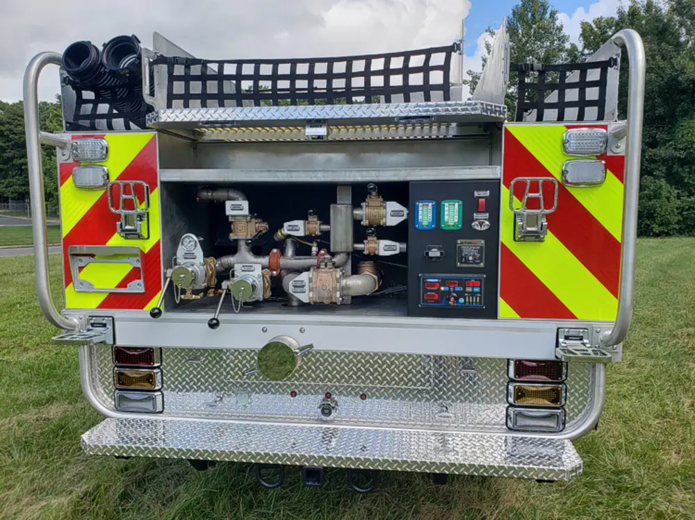 Exterior view of small fire truck showing cab, body compartments, and wheel/tire area.