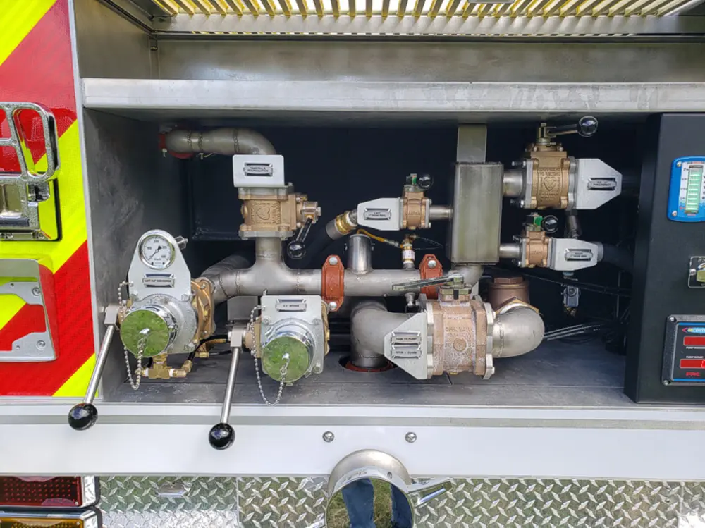 Exterior view of small fire truck showing cab, body compartments, and wheel/tire area.