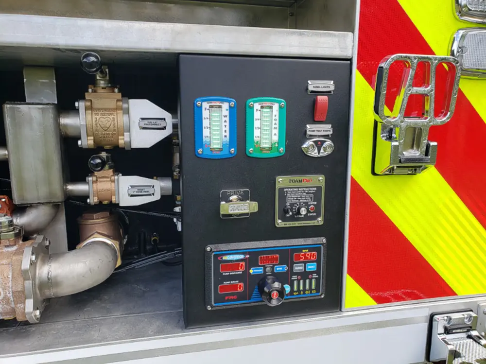 Exterior view of small fire truck showing cab, body compartments, and wheel/tire area.