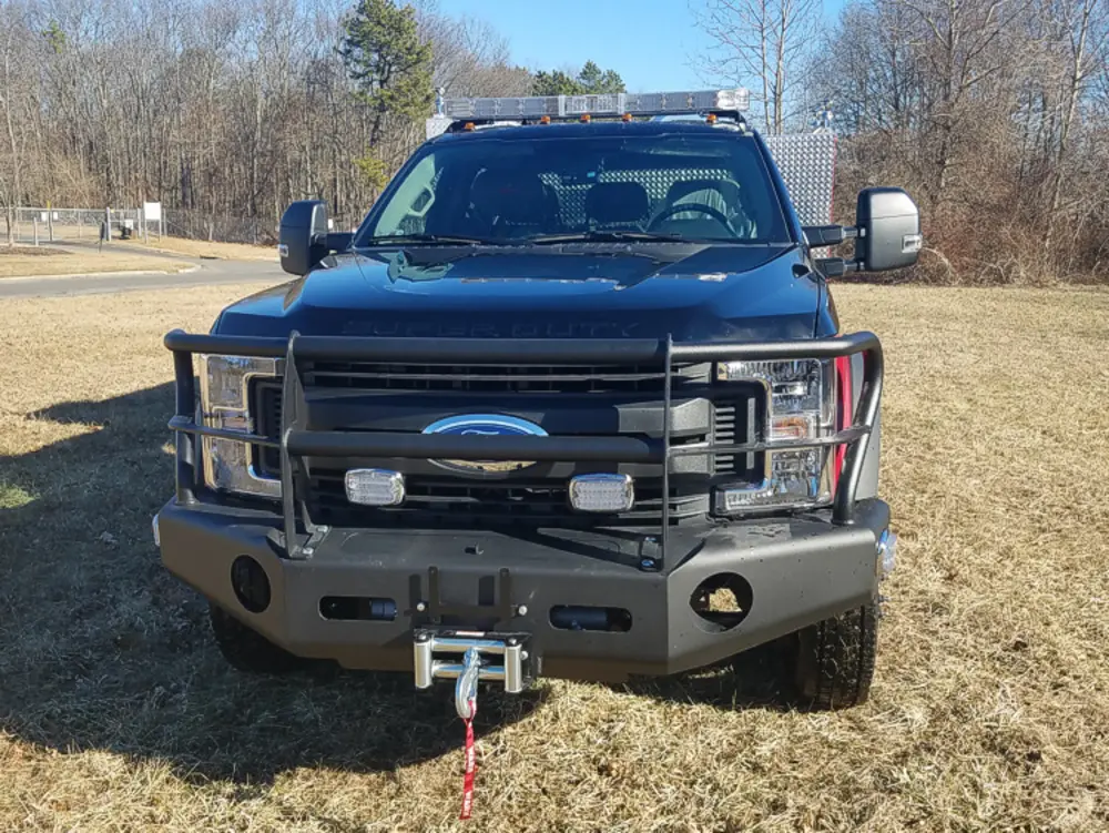 Exterior view of small fire truck showing cab, body compartments, and wheel/tire area.