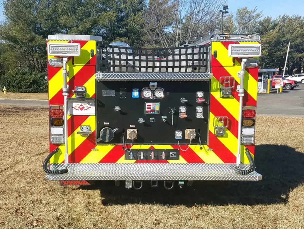 Exterior view of small fire truck showing cab, body compartments, and wheel/tire area.