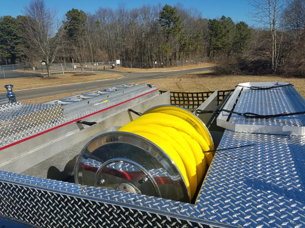 Exterior view of small fire truck showing cab, body compartments, and wheel/tire area.