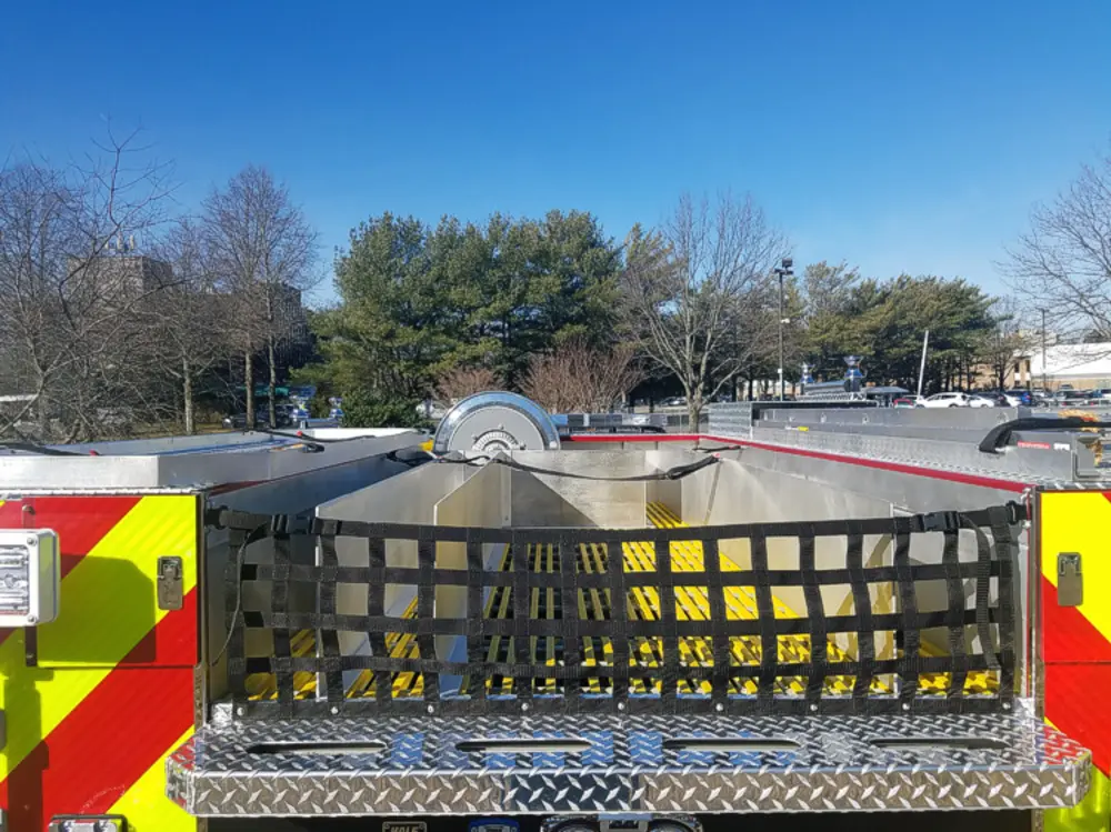 Exterior view of small fire truck showing cab, body compartments, and wheel/tire area.
