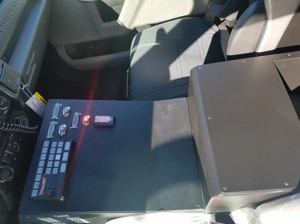 Exterior view of small fire truck showing cab, body compartments, and wheel/tire area.