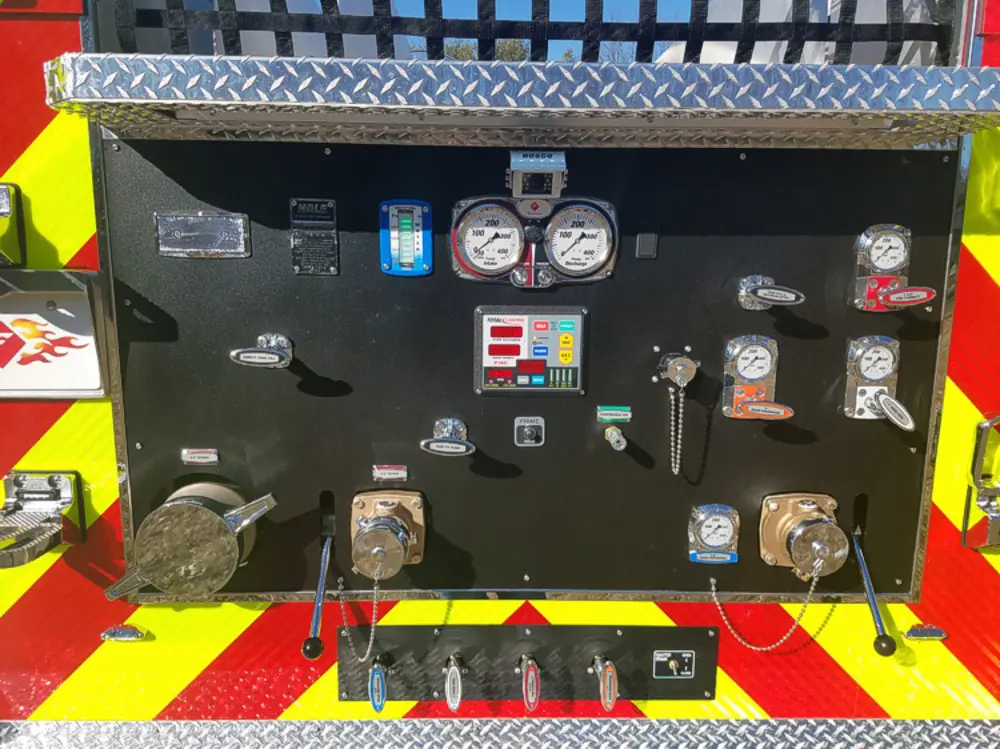 Exterior view of small fire truck showing cab, body compartments, and wheel/tire area.