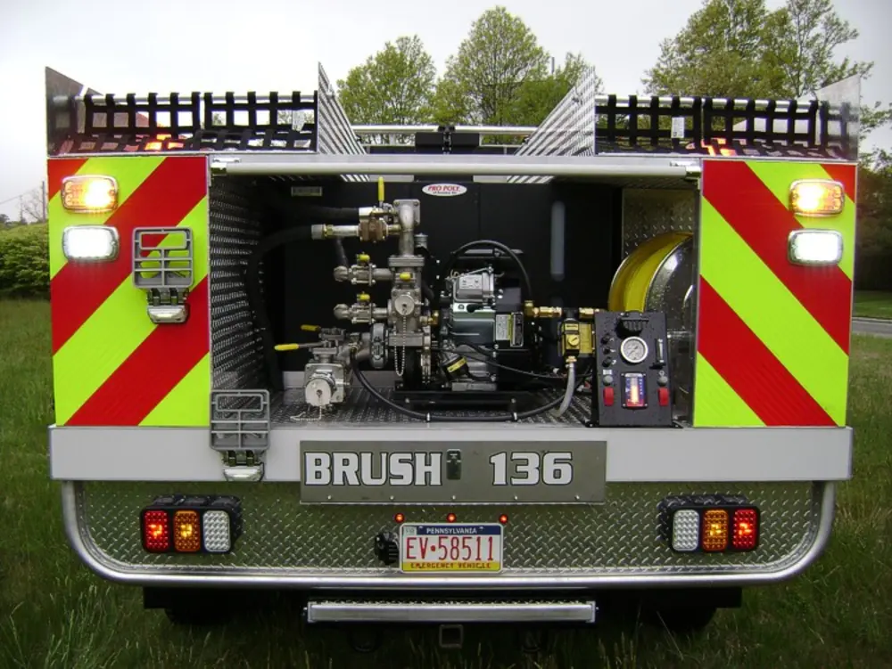 Exterior view of small fire truck showing cab, body compartments, and wheel/tire area.