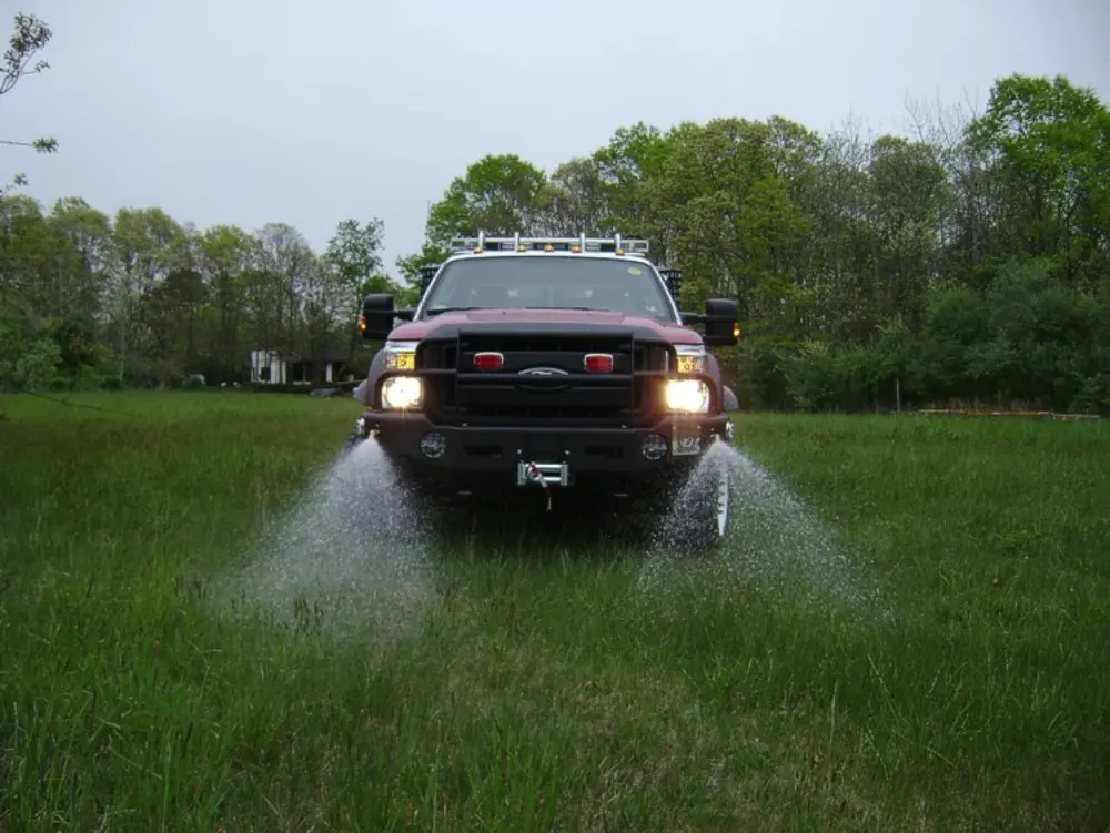 Exterior view of small fire truck showing cab, body compartments, and wheel/tire area.