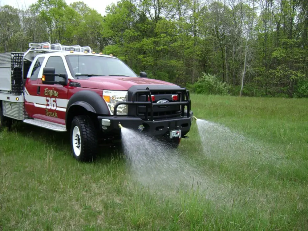 Exterior view of small fire truck showing cab, body compartments, and wheel/tire area.