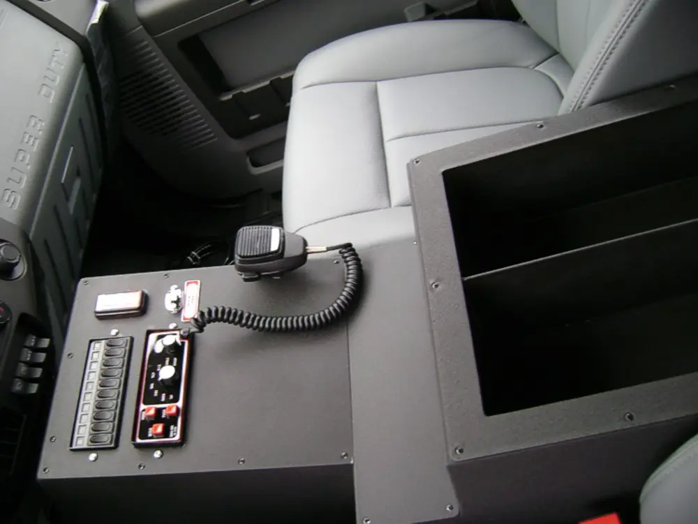 Exterior view of small fire truck showing cab, body compartments, and wheel/tire area.