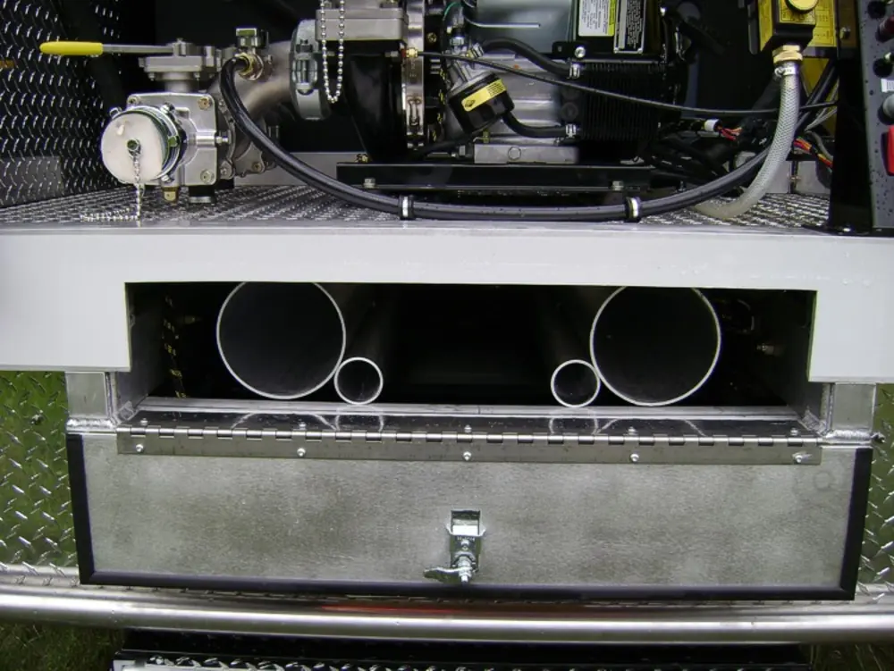 Exterior view of small fire truck showing cab, body compartments, and wheel/tire area.