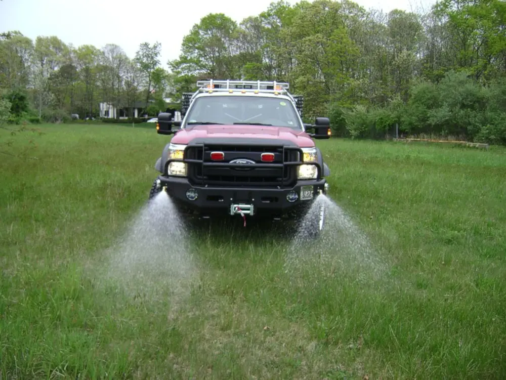 Exterior view of small fire truck showing cab, body compartments, and wheel/tire area.